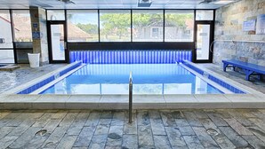 A swimming pool with a blue tiled edge, a drain in the center, and a stone floor. - Stylish Gulf-Front Condo w/ Balcony & Pools (Miramar Beach)