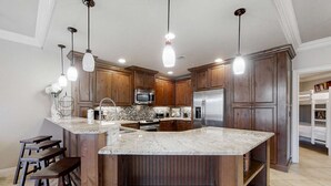 A kitchen with wooden cabinets, a granite countertop, stainless steel appliances, and pendant lighting. - Stylish Gulf-Front Condo w/ Balcony & Pools (Miramar Beach)