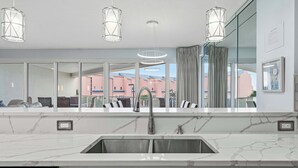 A modern kitchen with a marble countertop, stainless steel sink, and pendant lighting. - Exclusive beachfront: 2BR condo, pool, hot tub (Miramar Beach)