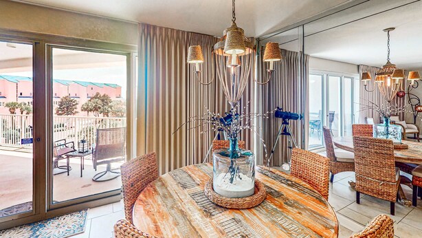 A dining area with a round table, wicker chairs, and a hanging light fixture. - Beachfront Luxury (Miramar Beach)