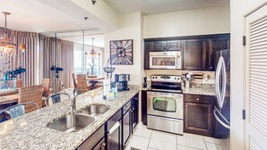 A modern kitchen with granite countertops, stainless steel appliances, and dark wooden cabinets. - Beachfront Luxury (Miramar Beach)
