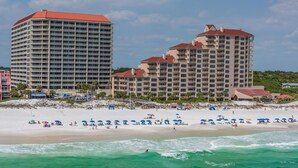 A beachfront hotel with multiple buildings, a sandy beach, and ocean waves. - Beachfront Luxury (Miramar Beach)