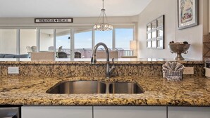 A kitchen with granite countertops, a stainless steel sink, and a chandelier. - Exclusive beachfront: Gulf views, sleeps 6 (Miramar Beach)