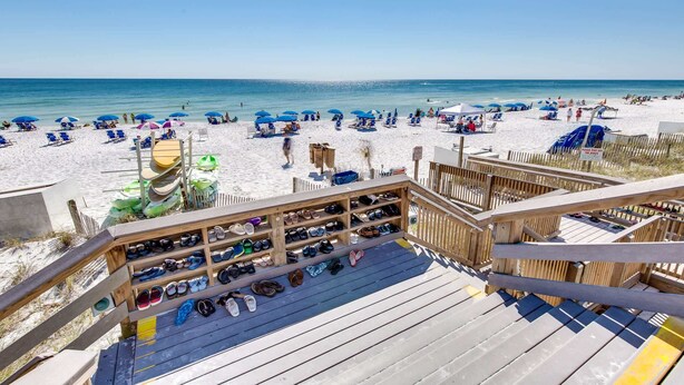 A beach view from a wooden deck with a shoe rack and umbrellas. - Exclusive beachfront: Gulf views, sleeps 6 (Miramar Beach)