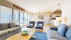 A modern living room with a sofa, two armchairs, a coffee table, and a view of the city. - Exclusive beachfront: Gulf views, sleeps 6 (Miramar Beach)