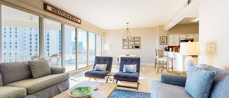 A modern living room with a sofa, two armchairs, a coffee table, and a view of the city.