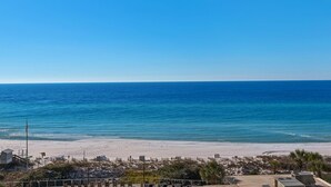 A beach view with a clear sky, sandy beach, and some buildings in the foreground. - Beachfront escape with Gulf views, pool access (Miramar Beach)