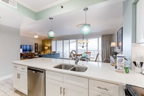 A modern kitchen with a large island, stainless steel appliances, and pendant lighting. - Beachfront escape with Gulf views, pool access (Miramar Beach)