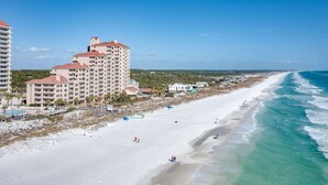 Ein Hotel direkt am Strand mit mehreren Gebäuden, einem Sandstrand und Wellen.