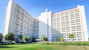 Un hôtel à plusieurs étages au design moderne, doté d’une cour intérieure avec des palmiers et d’une pelouse bien entretenue.