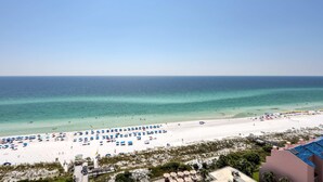 Ein Strand mit Sonnenschirmen und Liegestühlen, ein klarer Himmel und das Meer.