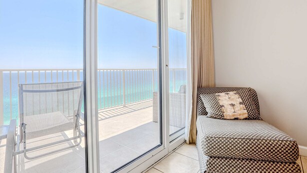 Ein Balkon mit Meerblick, ein Stuhl und eine Couch mit gemusterten Kissen.