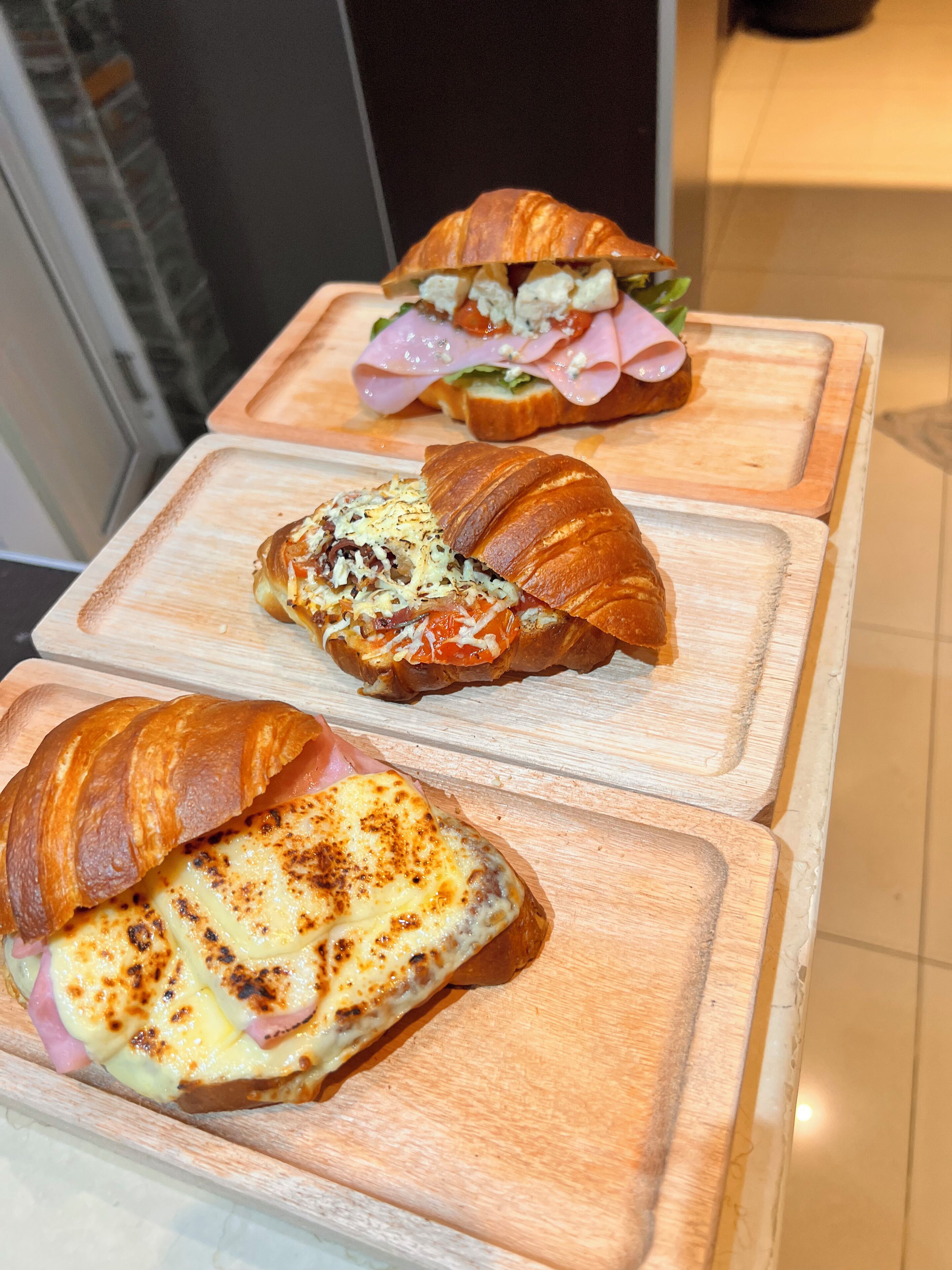 Tres sándwiches sobre tablas de madera.