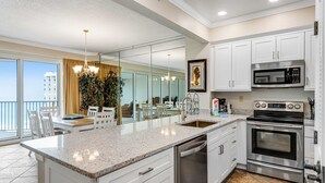 Una cocina moderna con armarios blancos, electrodomésticos de acero inoxidable y una isla grande con lavavajillas.