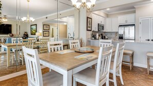 Una cocina amplia con armarios blancos, una isla central y una araña.