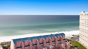 Een hotel aan het strand met meerdere balkons, een zwembad en uitzicht op de oceaan.