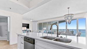 Een moderne keuken met een vaatwasser, dubbele spoelbak en een kroonluchter.