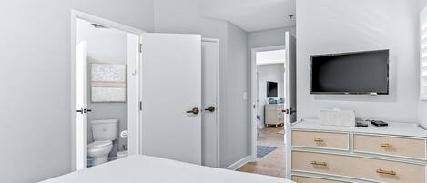 A modern bedroom with a bed, a TV mounted on the wall, and a dresser with drawers.