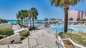 A pool area with steps leading down to the water, surrounded by palm trees and umbrellas. - Gulf-front condo: 2BR, pools, direct beach (Miramar Beach)