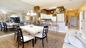 A spacious living area with a dining table, chairs, a sofa, and a kitchen in the background. - Gulf-front condo: 2BR, pools, direct beach (Miramar Beach)
