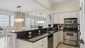 Una cocina moderna con armarios blancos, una estufa de acero inoxidable y una isla grande con encimera de granito.