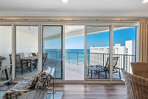 A balcony with a view of the ocean and buildings, furnished with a table, chairs, and a sofa. - Exclusive 2BR Oceanfront w/ Private Balcony (Miramar Beach)