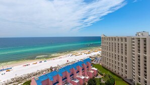 A beachfront hotel with a pool, beach umbrellas, and a view of the ocean. - 2BR Gulf-front condo with ocean views (Miramar Beach)