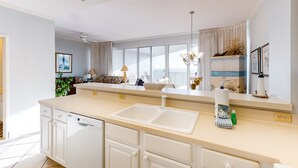 A modern kitchen with a large island, white cabinetry, and a view of the balcony. - 2BR Gulf-front condo with ocean views (Miramar Beach)
