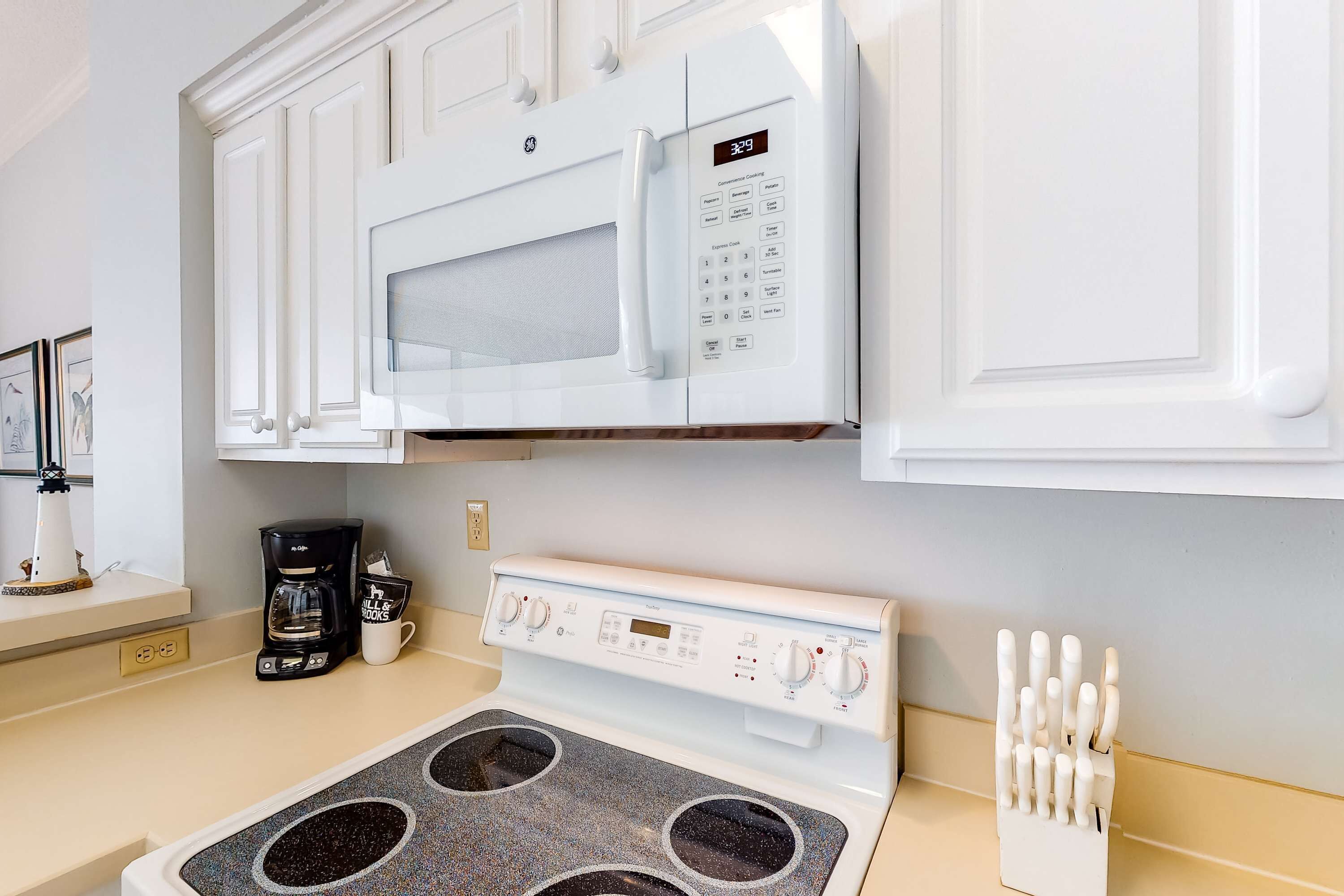 Una cocina con microondas, estufa y cafetera blancos.