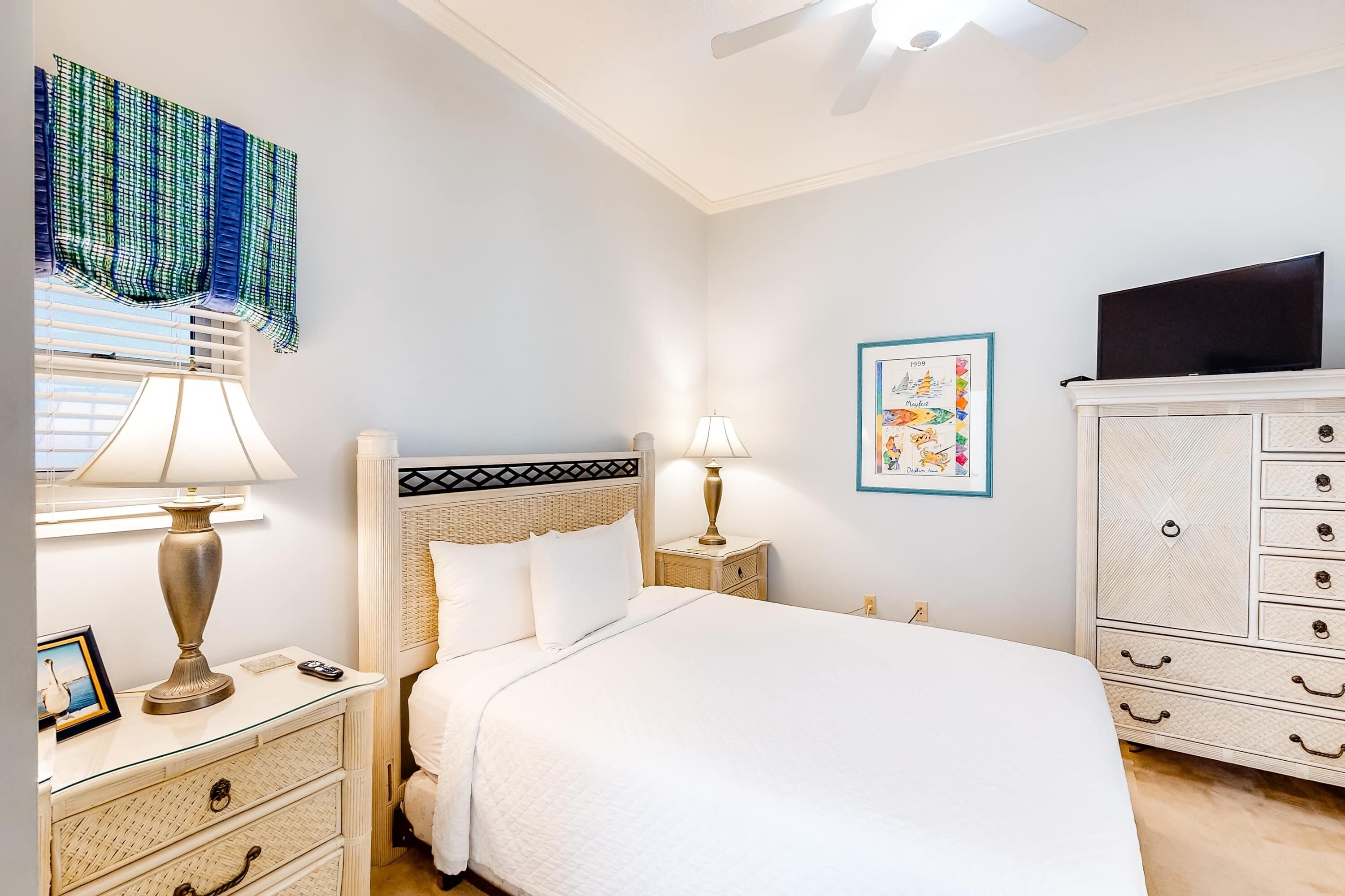 A neatly arranged bedroom with a bed, bedside tables, a lamp, a television, and a wardrobe.