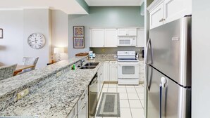 Una cocina moderna con armarios blancos, un refrigerador de acero inoxidable, un microondas y un horno empotrado.