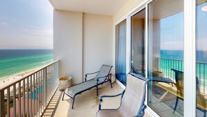 Un balcón con dos sillones, una mesita y vistas al océano.