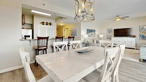 A dining area with a white table and chairs, a hanging light fixture, and a ceiling fan. - Beachfront Resort with Gulf Views & Pool (Miramar Beach)