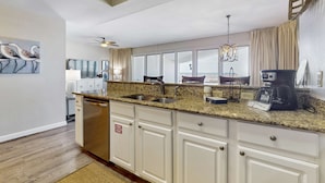 A modern kitchen with granite countertops, white cabinetry, and a large island with a sink. - Beachfront Resort with Gulf Views & Pool (Miramar Beach)