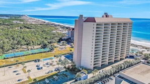 A high-rise hotel with a pool, parking lot, and beachfront view. - Beachfront Resort with Gulf Views & Pool (Miramar Beach)