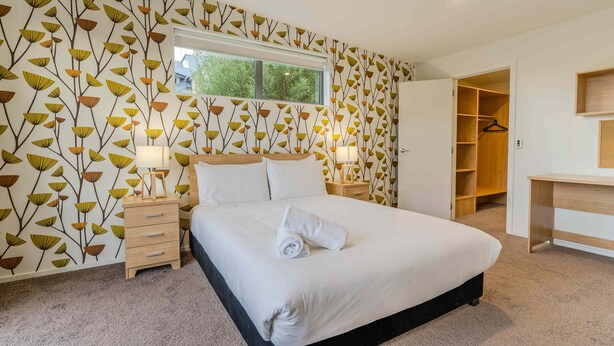 Una camera da letto con un letto grande, un comodino, una scrivania in legno e un armadio.