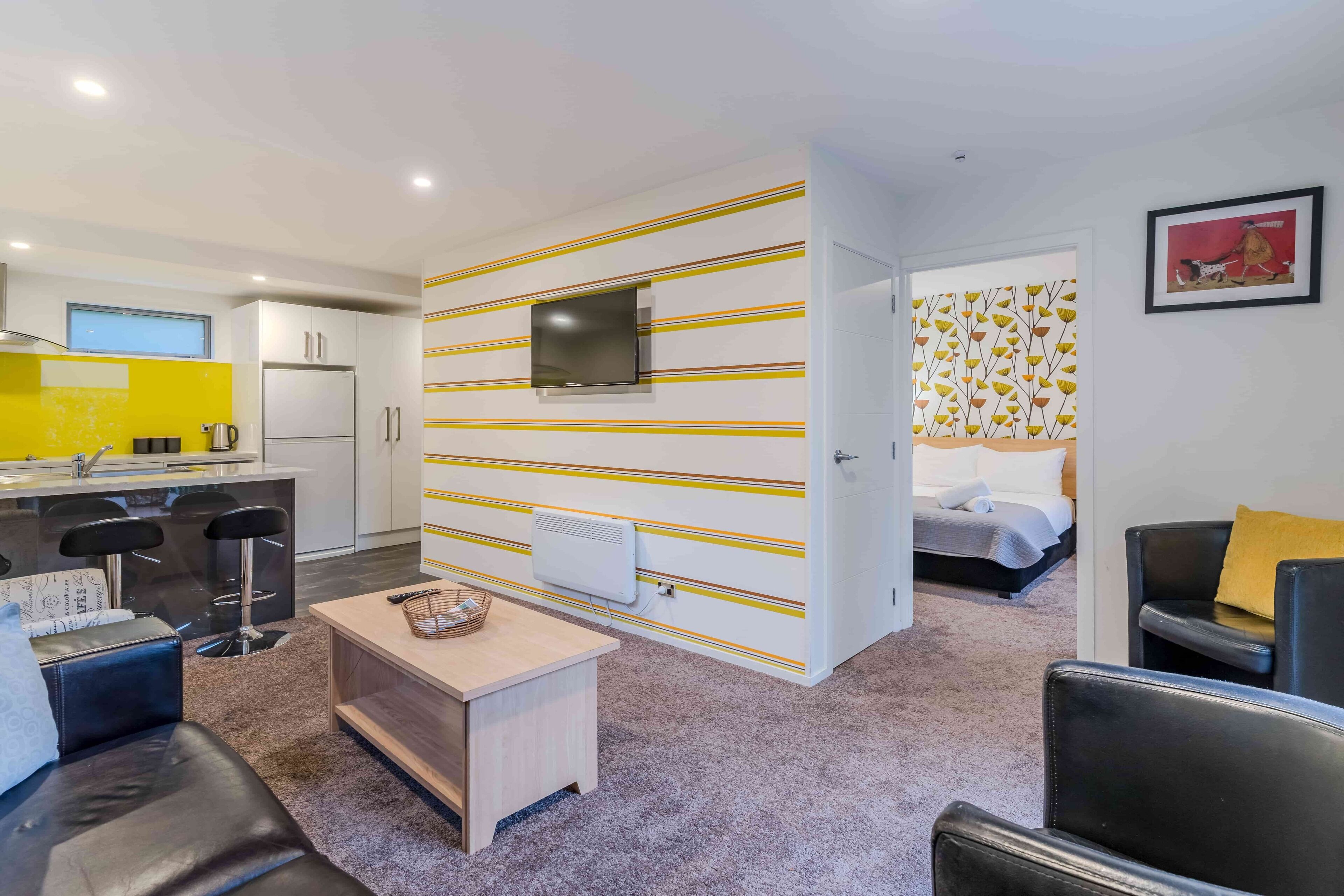 A compact living space with a kitchenette, a dining area, and a bedroom.