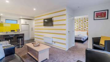 A compact living space with a kitchenette, a dining area, and a bedroom.