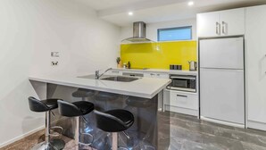 Una cucina moderna con isola centrale, sgabelli da bar, forno integrato e frigorifero.
