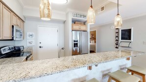 A modern kitchen with granite countertops, stainless steel appliances, and pendant lighting. - Exclusive 2BR beachfront condo with gulf views (Miramar Beach)
