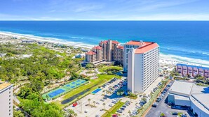 Un hotel costero con varios edificios altos, un estacionamiento y vistas a la playa.