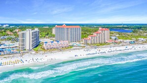 Un hotel frente al mar con varias edificaciones, una playa de arena y vistas al océano.