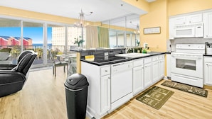 A modern kitchen with white cabinets, a black countertop, and a view of the city. - Beachfront condo with Gulf views (Miramar Beach)