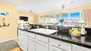 A modern kitchen with a large island, a double sink, and a view of the ocean. - Beachfront condo with Gulf views (Miramar Beach)
