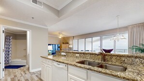 A modern kitchen with granite countertops, white cabinetry, and a large window offering a view. - Exclusive Gulf-Front Condo with Balcony (Miramar Beach)