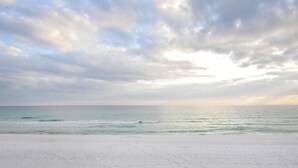 Ein Strand mit weitem, sandigen Uferbereich und ruhigem Meer unter einem bewölkten Himmel.