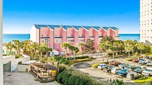 Vaaleanpunainen hotelli, jossa on pysäköintialue ja näkymä merelle.