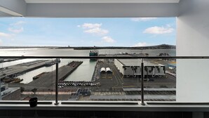 A view from a high window overlooking a port with shipping containers, a dock, and a building with a flat roof.