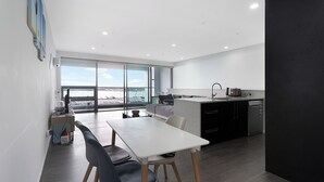 A modern kitchen with a dining area, large windows, and a view of the city.