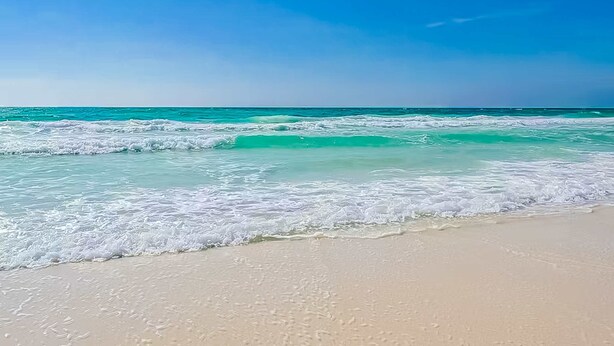 Ein Strand mit klarem türkisblauem Wasser und sandigem Ufer.
